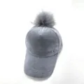 Detail der grauen Plüsch-Basecap mit flauschigem Bommel und Metall-M-Logo - Erwachsene / Grau