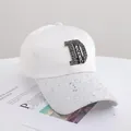 Detail der weißen Baseballkappe mit Strass-D-Logo und silbernen Pailletten am Schirm - Erwachsenengröße (56-58cm) / Weiß