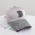 Detail der Baseballkappe mit schimmerndem silbernen D-Logo und glatter Satinstruktur - Erwachsenengröße (56-58cm) / Grau