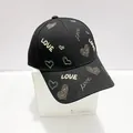 Dettaglio del ricamo a cuore e LOVE sul berretto da baseball nero strutturato - Taglia Adulto (Regolabile) / Nero Filo d'Oro