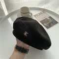 Dettaglio di un basco nero in lana con elegante logo metallico dorato a forma di K - M / Nero