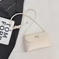 Elegante crèmewitte mini-crossbodytas met metalen strikje op een stijlvolle achtergrond - Broken Wit