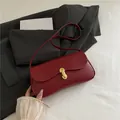 Bolso de hombro burdeos minimalista con hebilla dorada sobre una chaqueta gris - Rojo