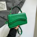 Grass green crossbody bag with wave-quilted flap and gold hardware held by hand - Green