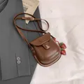 Brown vintage leather saddle bag with adjustable strap and strawberry charm detail - Strawberry Pendant / Brown with Pendant