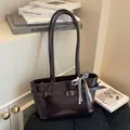 Minimalistische donkerbruine leren tote bag met metalen gesp en geruite lintstrik - koffiekleur