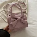 Elegante hellrosa Handtasche mit Schleife, glitzerndem Finish und goldenen Metallteilen - Rosa