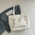 Borsa tote bianca testurizzata con tasca frontale e lacci decorativi su sfondo denim - Bianco