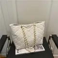 Sac cabas blanc matelassé avec bandoulière chaîne posé sur une chaise noire moderne - Blanc