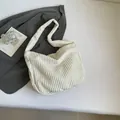 Minimalist beige corduroy tote bag for women shown on a dark grey blazer backdrop - White