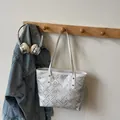 Silver metallic tote bag with geometric patterns hanging on a wooden coat rack - Off White