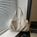 Bolso tote grande beige minimalista mostrado con ordenador portátil bajo luz suave - Blanco