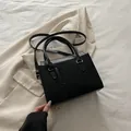 Elegante schwarze minimalistische Handtasche mit Wildledertextur und Goldlogo - Schwarz