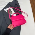 Elegante borsa a tracolla magenta con manico intrecciato su sfondo blazer antracite - Rosa Rosso