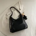 Borsa tote in morbida pelle nera con ciondolo a gattino su sfondo di blazer beige - Nero