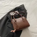 Braune Tragetasche mit Krokodilprägung und verstellbarem Riemen auf schwarzem Blazer - Dunkelbraun