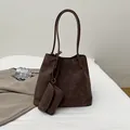 Sac cabas marron foncé mat avec pochette assortie sur une literie blanche épurée - Marron