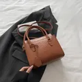 Sac à main marron à motif crocodile avec lettrage doré sur un blazer noir chic - Beige