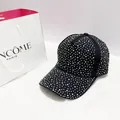 Detailed close-up of a black baseball cap featuring dense sparkling rhinestone embellishments - Black