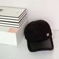 Détail d'une casquette en molleton noir avec visière en cuir et lettre M dorée - 58cm (Ajustable) / Noir