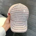 Detailed view of hand-held pink baseball cap featuring rows of white pearls and rhinestones - Adult Size (Adjustable) / Pink AB Iridescent Pearl