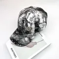 Detalle de gorra tie-dye con diamantes de imitación brillantes y escudo metálico sobre revista - Talla Adulto (Ajustable) / Negro