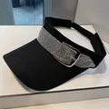 Detail of black visor hat with rhinestone band and silver buckle on white surface - Adult, Adjustable / Black