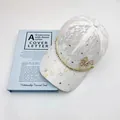 White lace baseball cap with golden rhinestone chain and sparkling clover accents - White