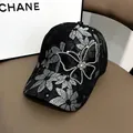 Détail d'une casquette en dentelle noire avec fleurs blanches et papillon en strass - Taille Adulte (Réglable) / Noir