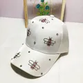 Detail of white satin baseball cap featuring rhinestone bee motifs and shimmering crystals - Adult Size (Adjustable) / White
