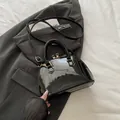 Borsa a conchiglia in vernice nera lucida con hardware dorato e tracolla - Nero