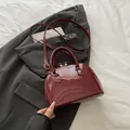 Borsa a conchiglia bordeaux in pelle verniciata con hardware dorato e tracolla lunga - Rosso