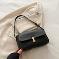 Minimalist black faux leather shoulder bag with a striking gold U-shaped metal buckle - Black