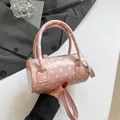 Pink polka dot barrel bag in glossy faux leather with dual handles and slim shoulder strap - Pink