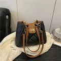 Bolso tote acolchado con correas marrones y cadena dorada en un sofá de cuero - Negro