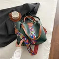 Dunkelgrüne Lederhandtasche mit braunen Griffen und buntem gewebtem Schultergurt - Grün