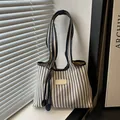 Bolso tote de lona a rayas con asas de cuero bajo luz natural de una ventana - Azul