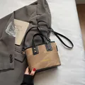 Bolso saco de lona marrón con ribete de cuero negro y remaches dorados en cama blanca - Caqui (Sin Colgante)