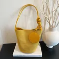 Modern bright yellow suede bucket bag with round coin purse and woven knotted strap detail - Yellow
