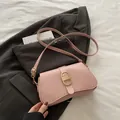 Elegante hellrosa Lederschultertasche mit goldener Schließe auf grauem Sakko - Rosa