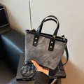 Minimalist grey denim bucket bag with black leather trim and golden rivets on the straps - Dark Brown