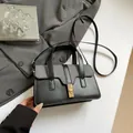 Bolso de mano en contraste negro y gris con cierre de giro dorado y correa - Negro