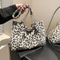 Chic leopard print tote bag with metal chain and pearl charm on a textured shoulder bag - White