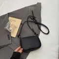 Schwarze Umhängetasche aus genarbtem Leder mit Knotengurt und minimalistischem Design - Schwarz