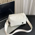 Minimalistische gebroken witte nylon crossbodytas met brede riem op een bureau - Wit