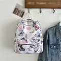 Witte nylon rugzak met kleurrijke vlinderprint en gouden ritsen in een lifestyle setting - Bloem Vlinder