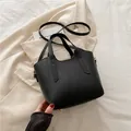 Bolso negro con textura litchi, detalles dorados y correa ajustable de estilo elegante - Negro