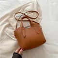 Bolso cubo marrón con textura lichi, asa superior y herrajes dorados en estilo de vida - Marrón