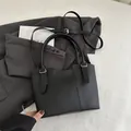 Classic black bucket bag in lychee pattern leather with dual handles and shoulder strap - Black