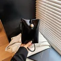 Glossy black mini crossbody phone bag with large pearl buckle and thin shoulder strap - Black